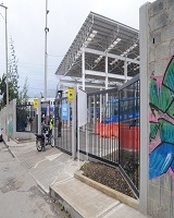 Fotografía que muestra de izquierda a derecha una vía vehicular, luego un portor que conduce a un patio del  Sistema Integrado de Transporte Público de Bogotá (SITP)