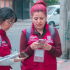 funcionarios de la Secretaría Distrital de Planeación con chaleco Vinotinto, realizando encuesta de Sisbén a un ciudadano sonriente. 