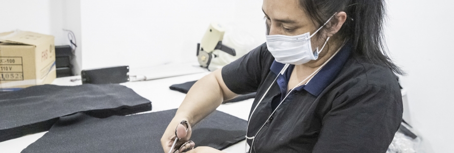 Mujer operaria de la industria textil cortando telas.
