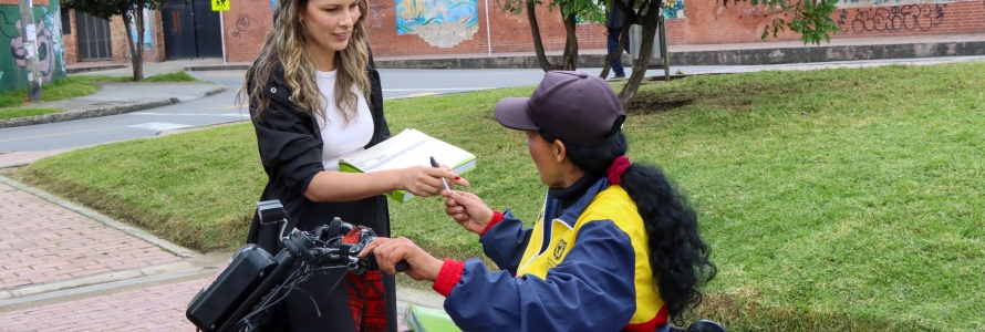 Jefe de la Oficina Asesora de Comunicaciones, Leidy Muñoz, entregando libro del Manual del Espacio Público a mujer en silla de ruedas.