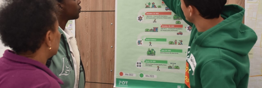 Funcionario de la Secretaría Distrital de Planeación explicando cartel a ciudadanas.